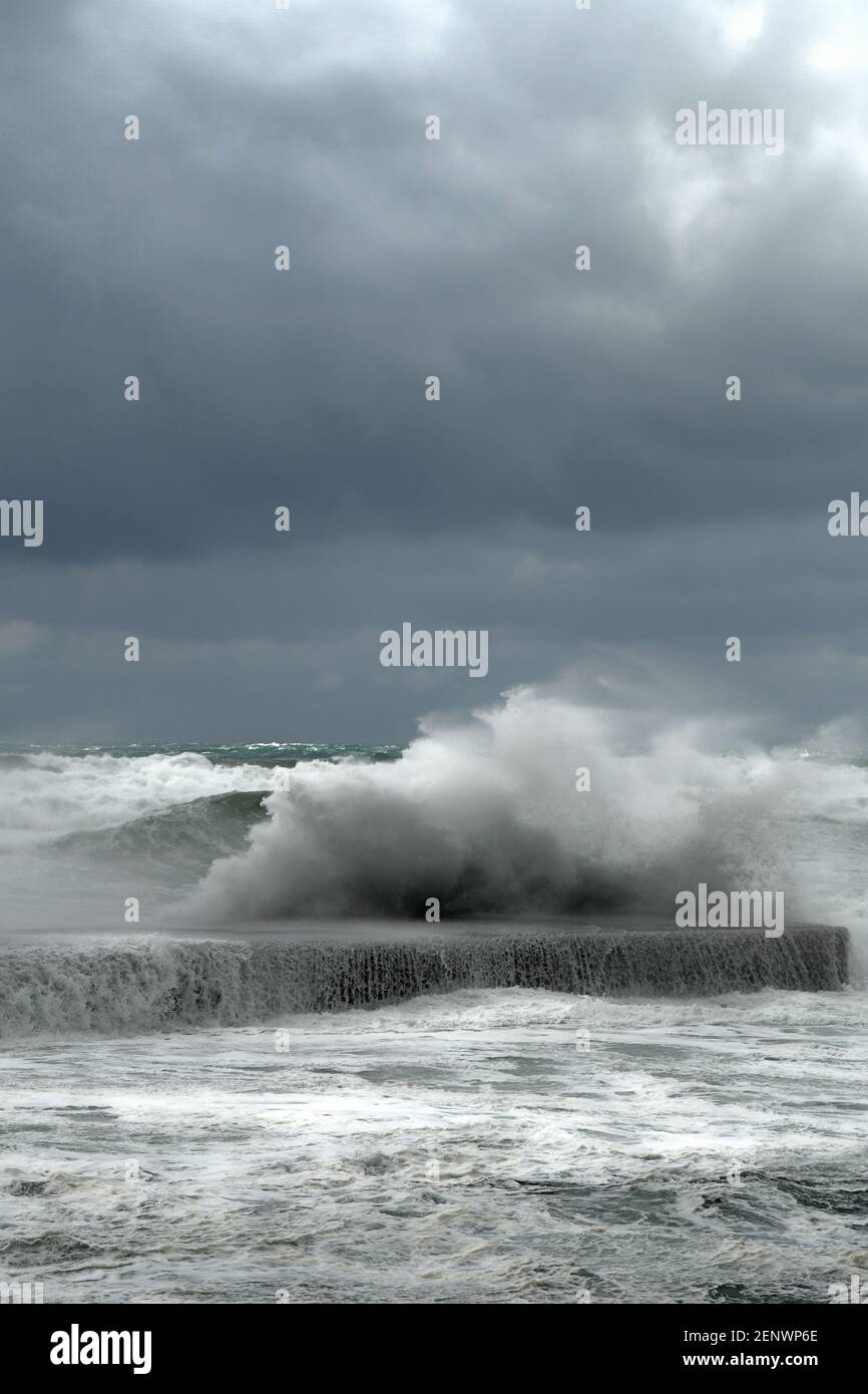 Rottura dell'onda sul muro di pietra in un giorno d'inverno tempestoso Foto Stock