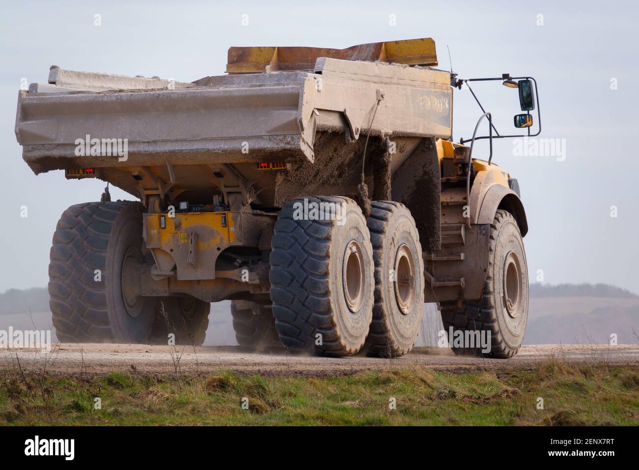 Gialle Volvo A40E dumper a terra articolato completamente carico con 25 tonnellate di carico che guida attraverso Salisbury Plain, Wiltshire UK Foto Stock