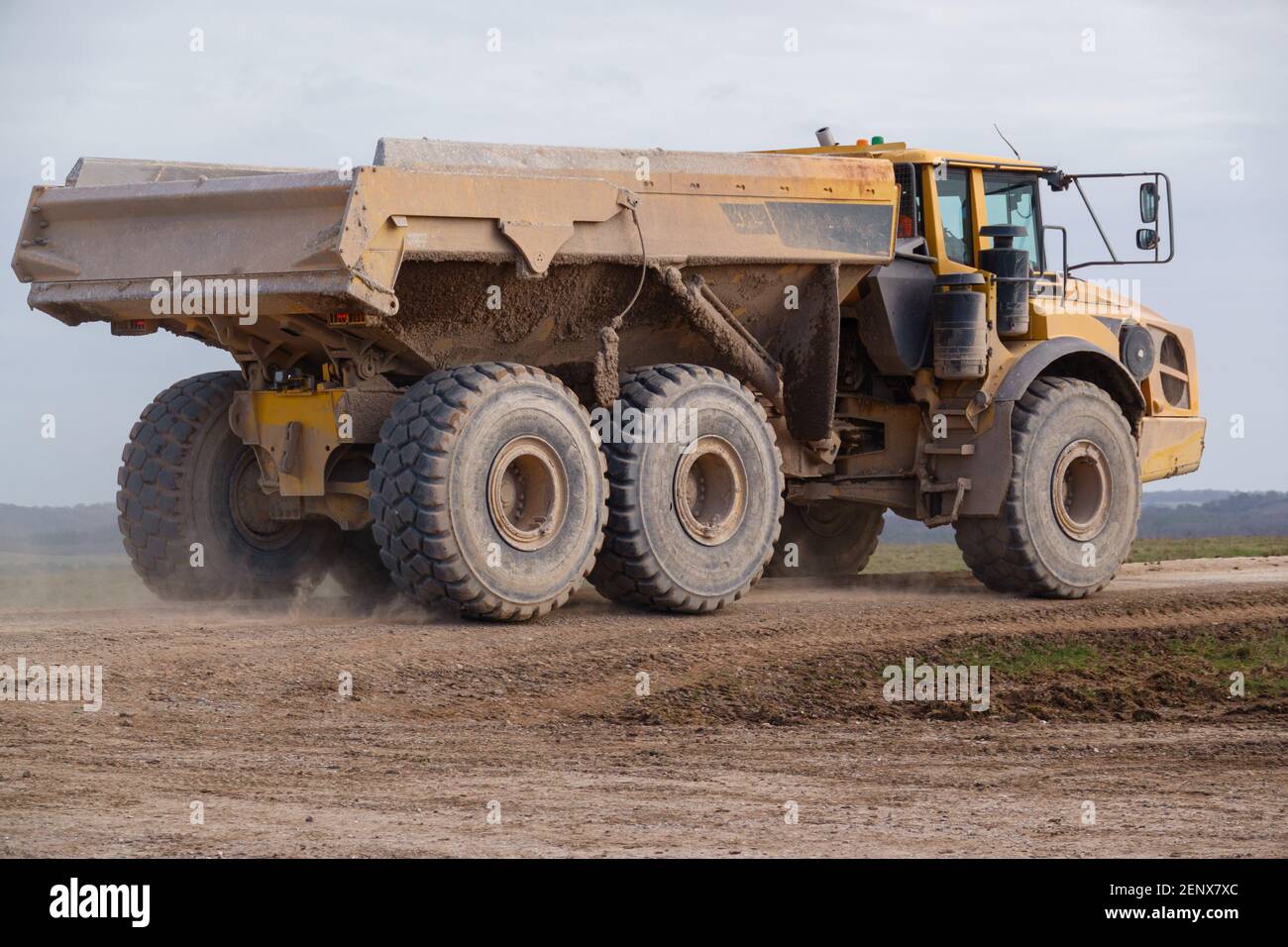 Gialle Volvo A40E dumper a terra articolato completamente carico con 25 tonnellate di carico che guida attraverso Salisbury Plain, Wiltshire UK Foto Stock