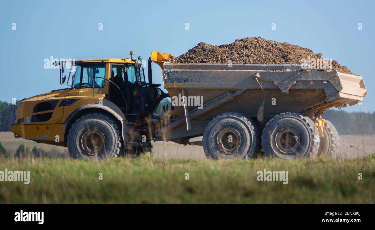 Gialle Volvo A40E dumper a terra articolato completamente carico con 25 tonnellate di carico che guida attraverso Salisbury Plain, Wiltshire UK Foto Stock