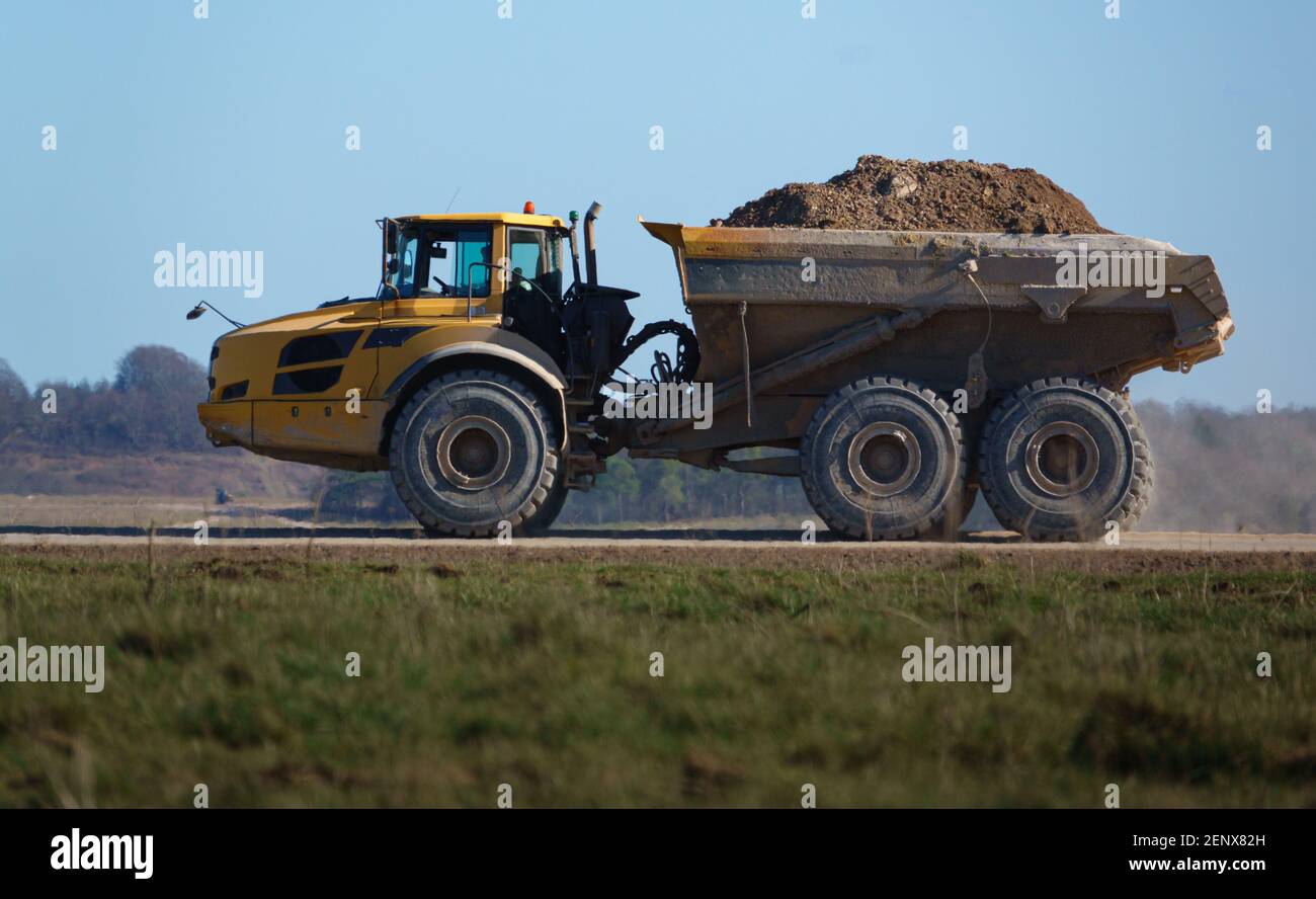 Gialle Volvo A40E dumper a terra articolato completamente carico con 25 tonnellate di carico che guida attraverso Salisbury Plain, Wiltshire UK Foto Stock