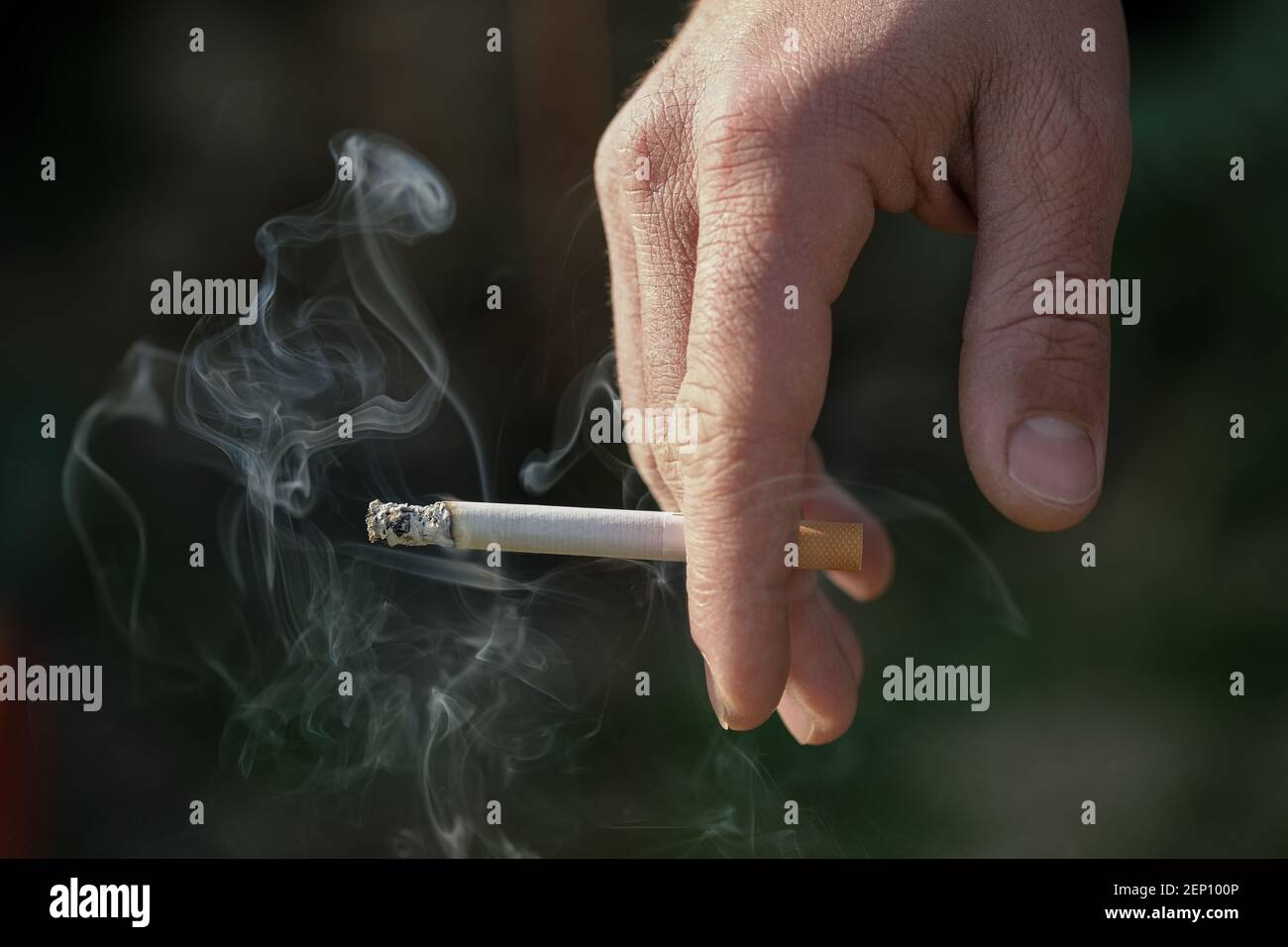 L'uomo tiene la mano che brucia la sigaretta mentre fuma, fumo di tabacco dipendenza, stile di vita malsano Foto Stock