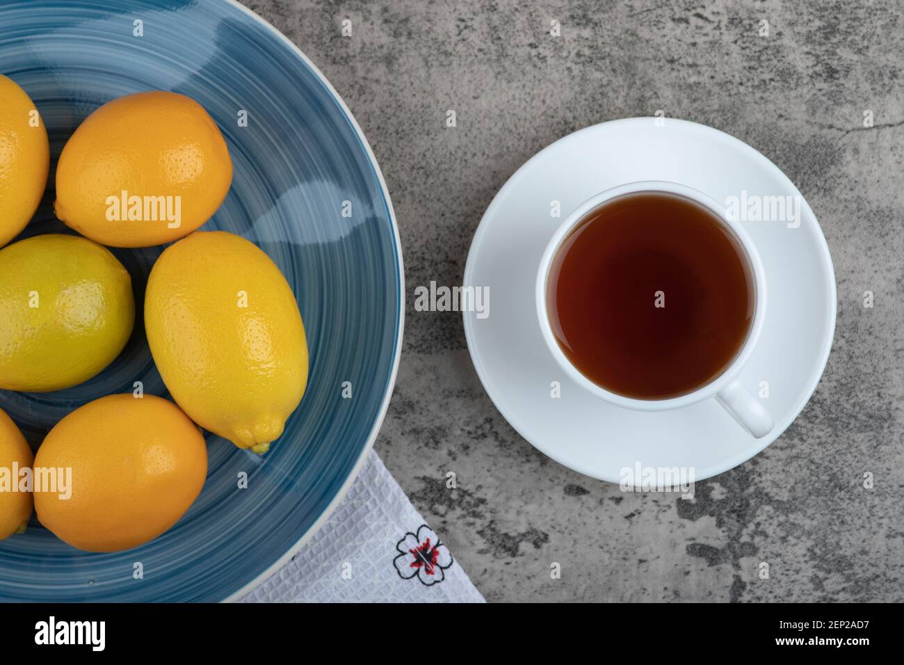 Tazza di tè caldo e piatto di limoni freschi su superficie in pietra Foto Stock