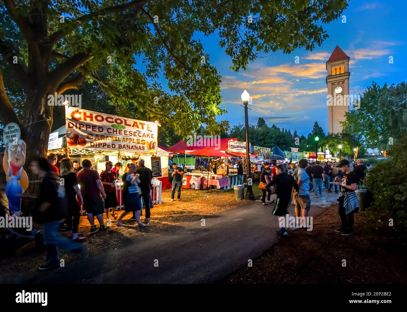 Notte al Pig out nel Park Festival mentre i turisti si godono le bancarelle e le bancarelle di cibo illuminato con la torre a spirale dietro a Spokane Washington. Foto Stock