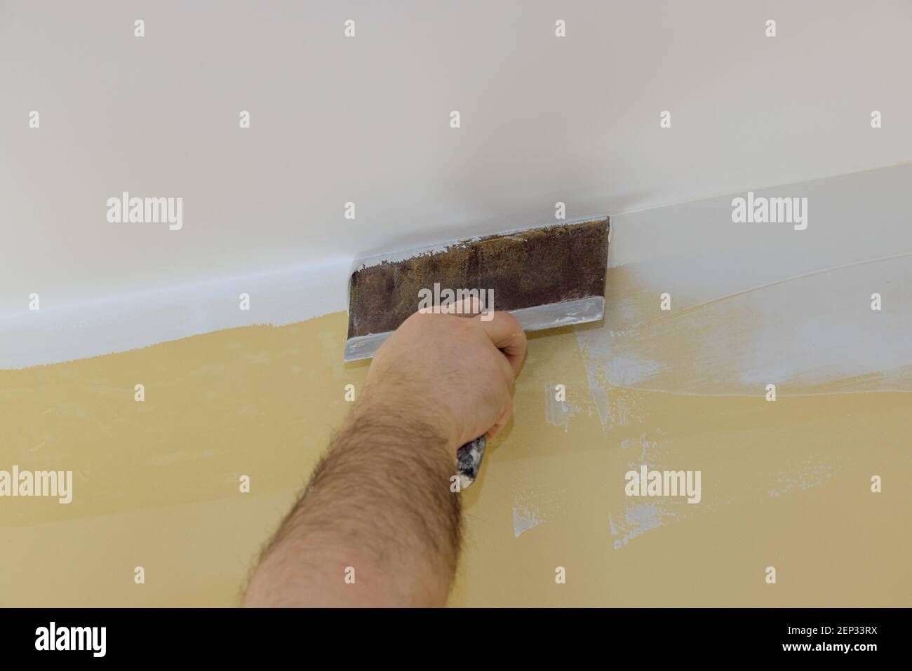 Il costruttore professionale leviga la parete con stucco a spatola messo su una superficie livellata di riparazione della parete nel proprio appartamento. Foto Stock
