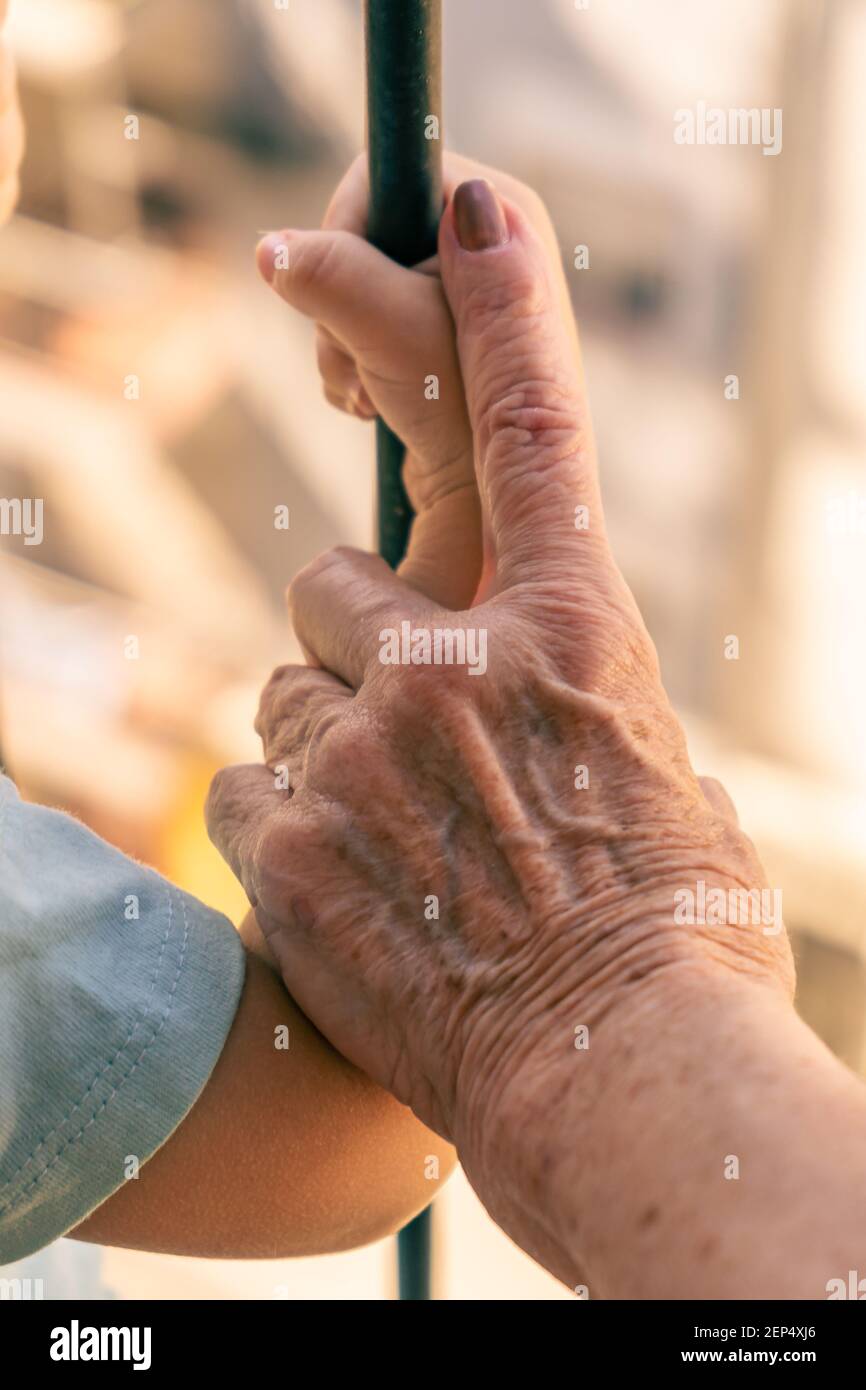La mano della vecchia donna che prende il braccio di un bambino. Concetto di cura e differenza di età. Primo piano Foto Stock