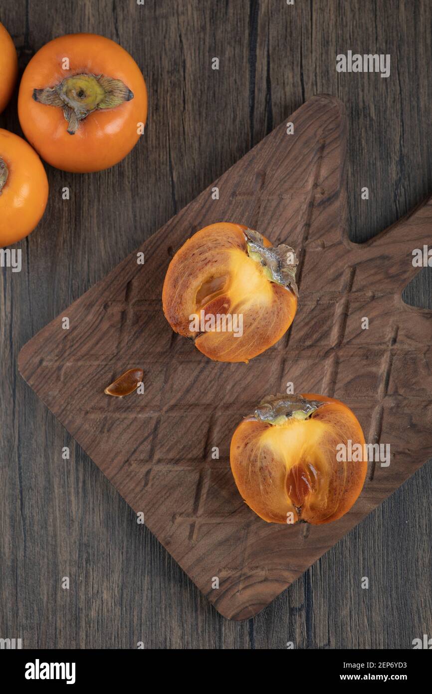 Frutta fuyu persimmon a metà fette su tagliere di legno Foto Stock