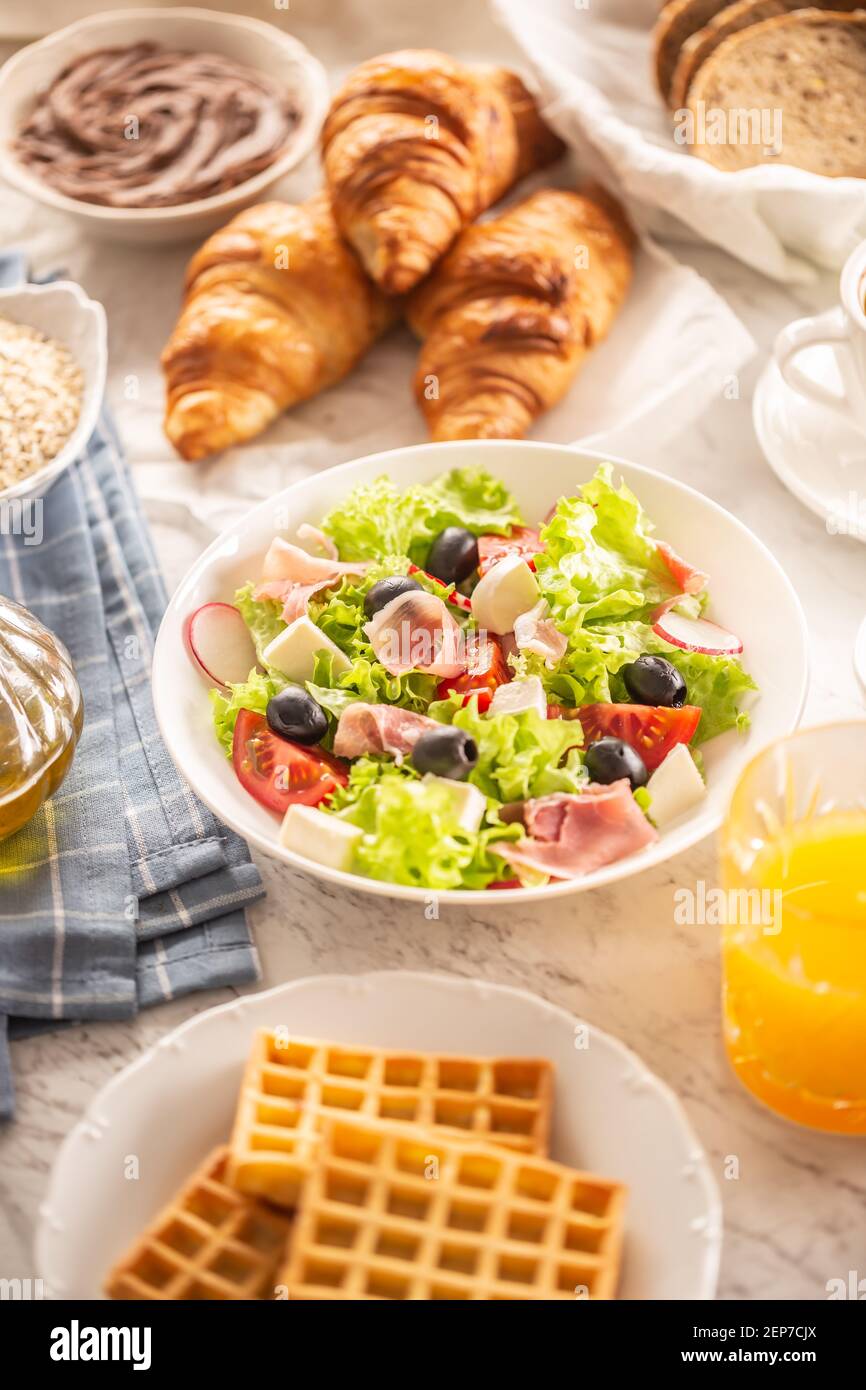 Ricca colazione con insalata, croissant, waffle, pane e succo d'arancia Foto Stock