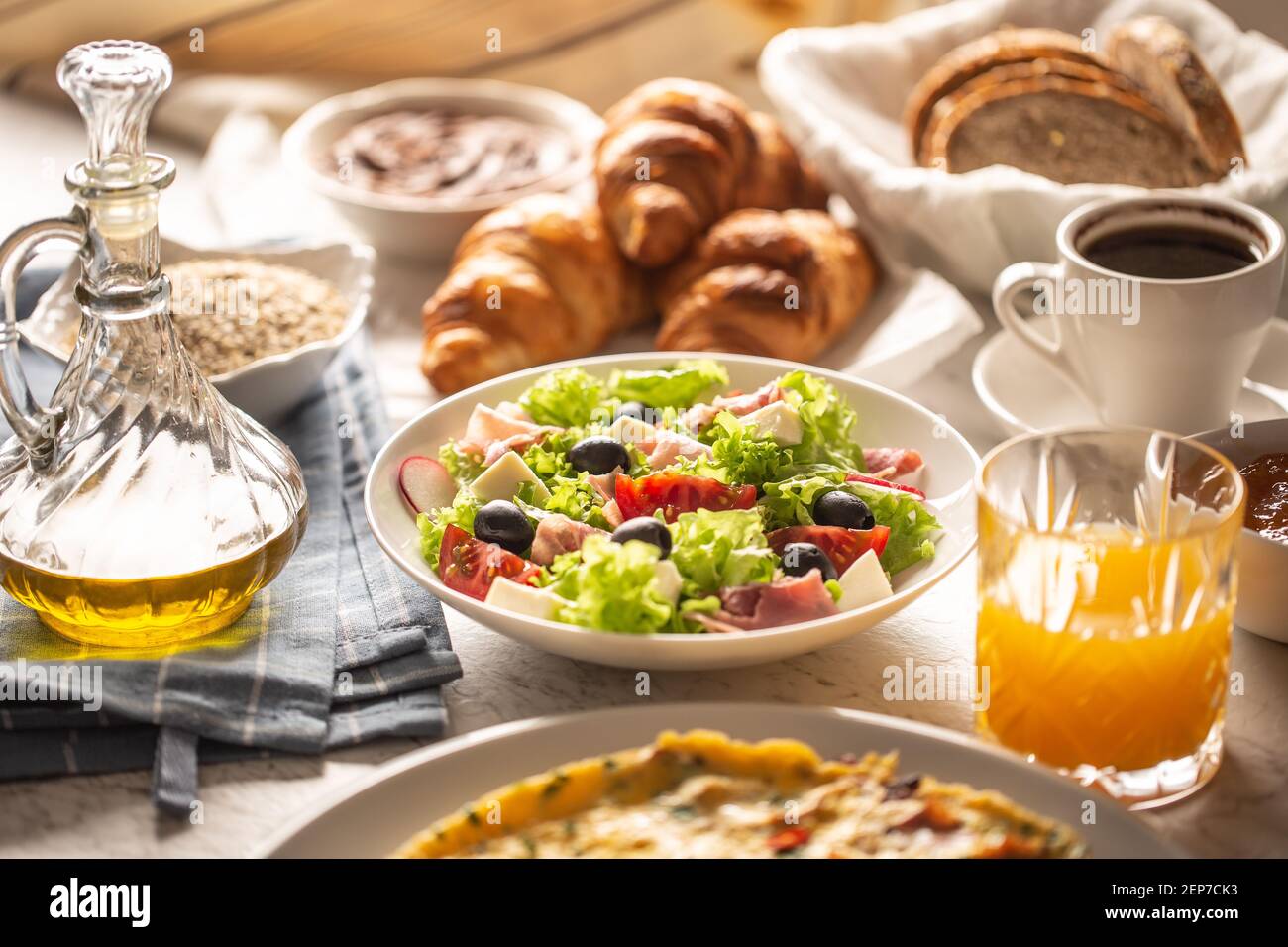 Ampio assortimento di cibi tra cui omelette, croissant, insalata, pane, farinata d'avena, vengono serviti marmellata, waffle, miele, chocolate, caffè e succo d'arancia Foto Stock