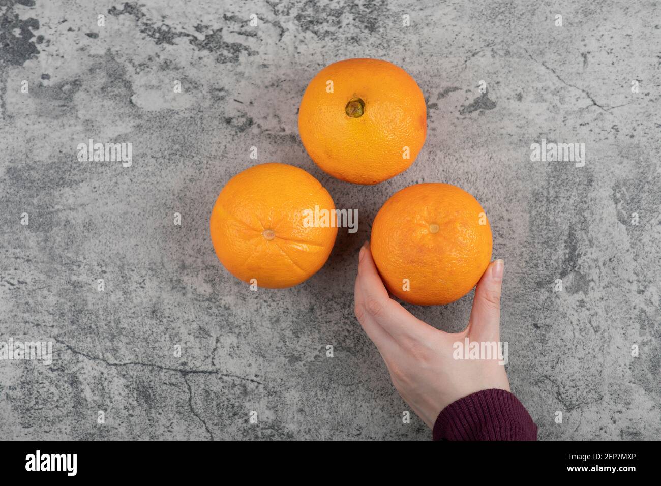 Mano di donna che prende una frutta fresca di arancia su tavola di pietra Foto Stock