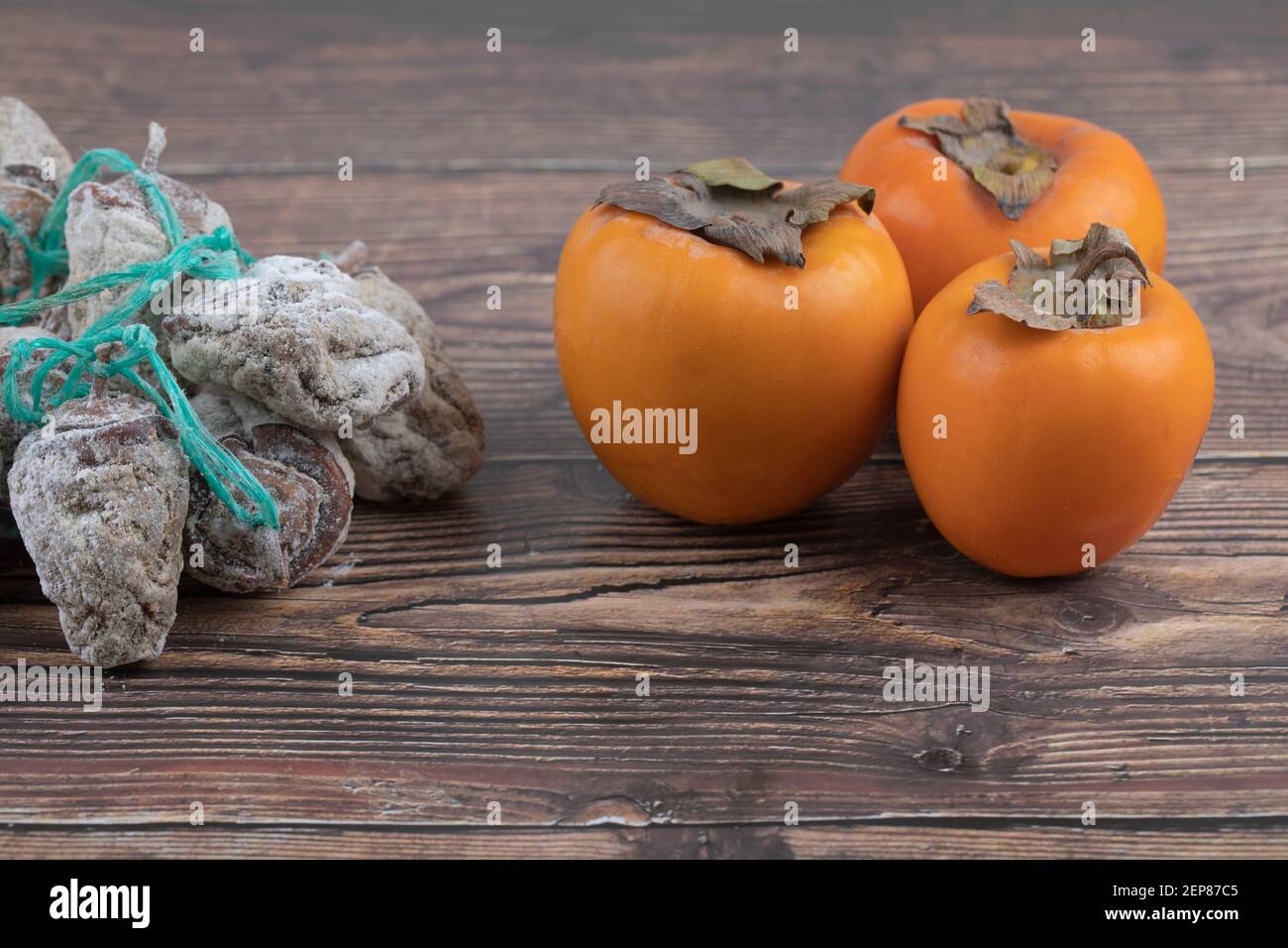 Gustosi persimmons fuyu e persimmons secchi su superficie di legno Foto Stock