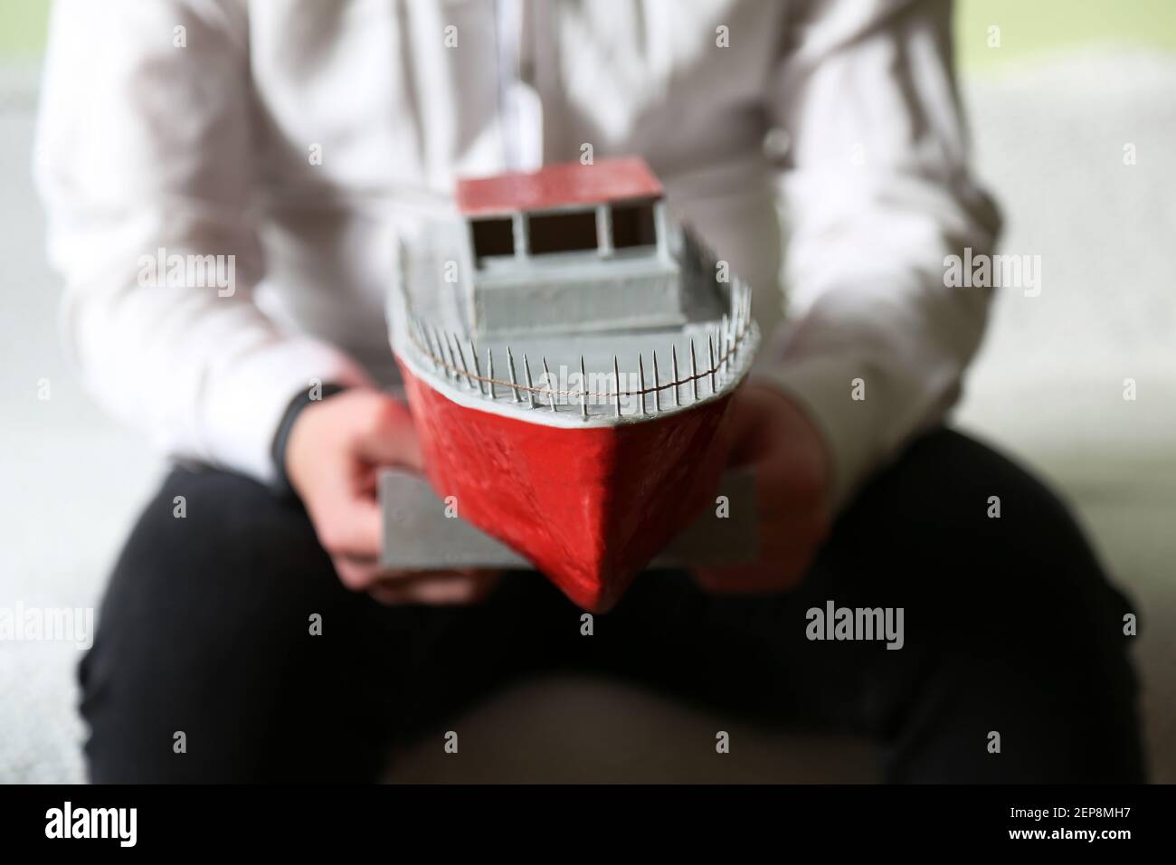 Il ragazzo sta tenendo una nave improvvisata. Uno yacht fatto da un ragazzo. Una nave giocattolo. Foto Stock