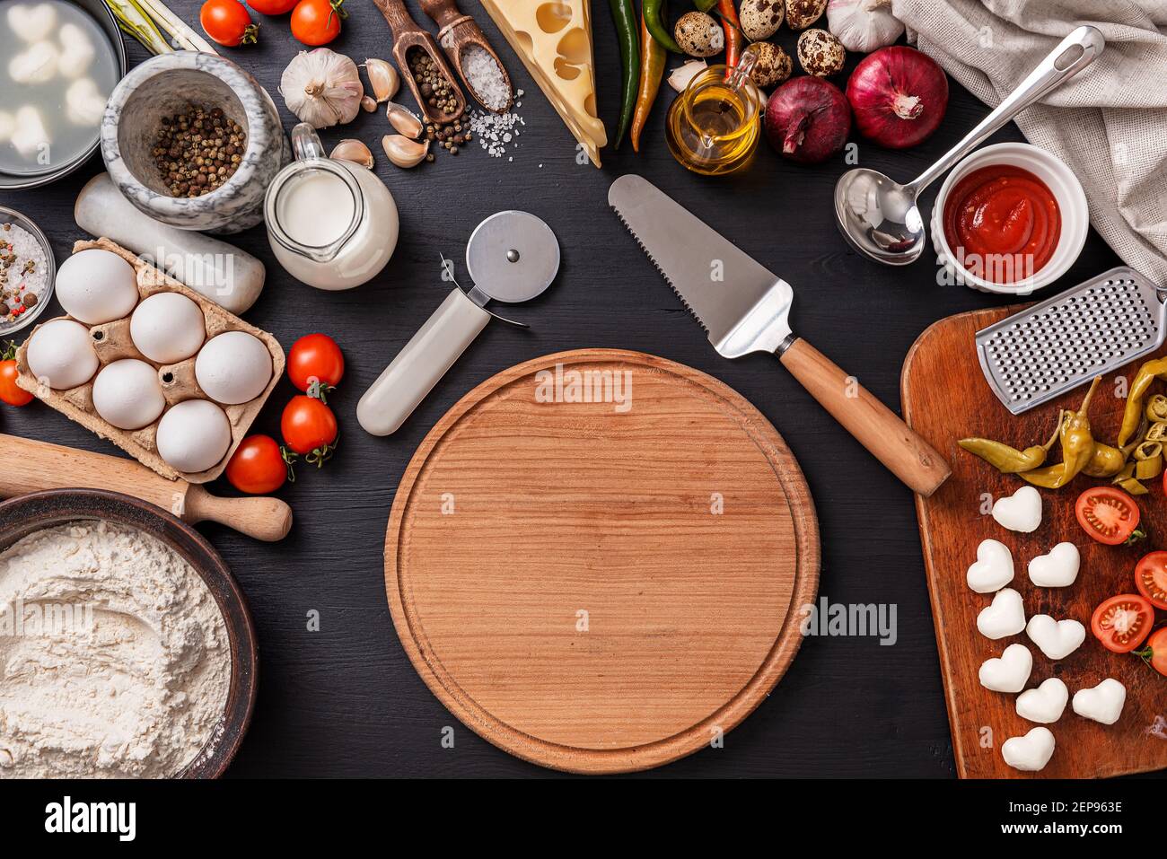 Pizza classica margherita con formaggio a forma di cuore. Preparazione di una cena di gala a fasi per due a casa in onore del giorno di San Valentino. Foto Stock