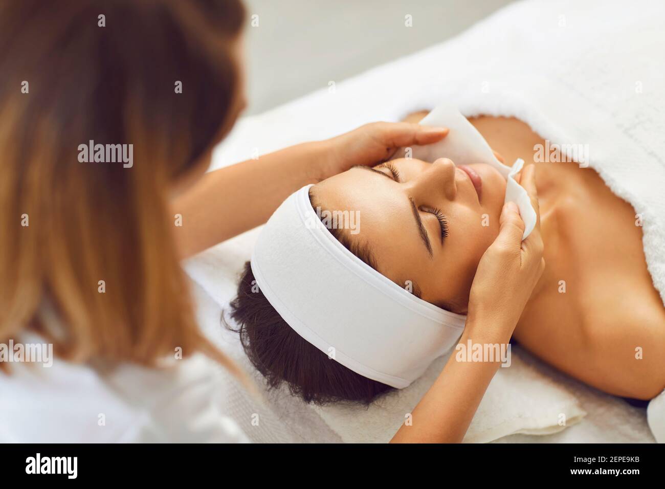Donna estetista lava il viso di una donna che si prepara per una procedura cosmetica. Foto Stock