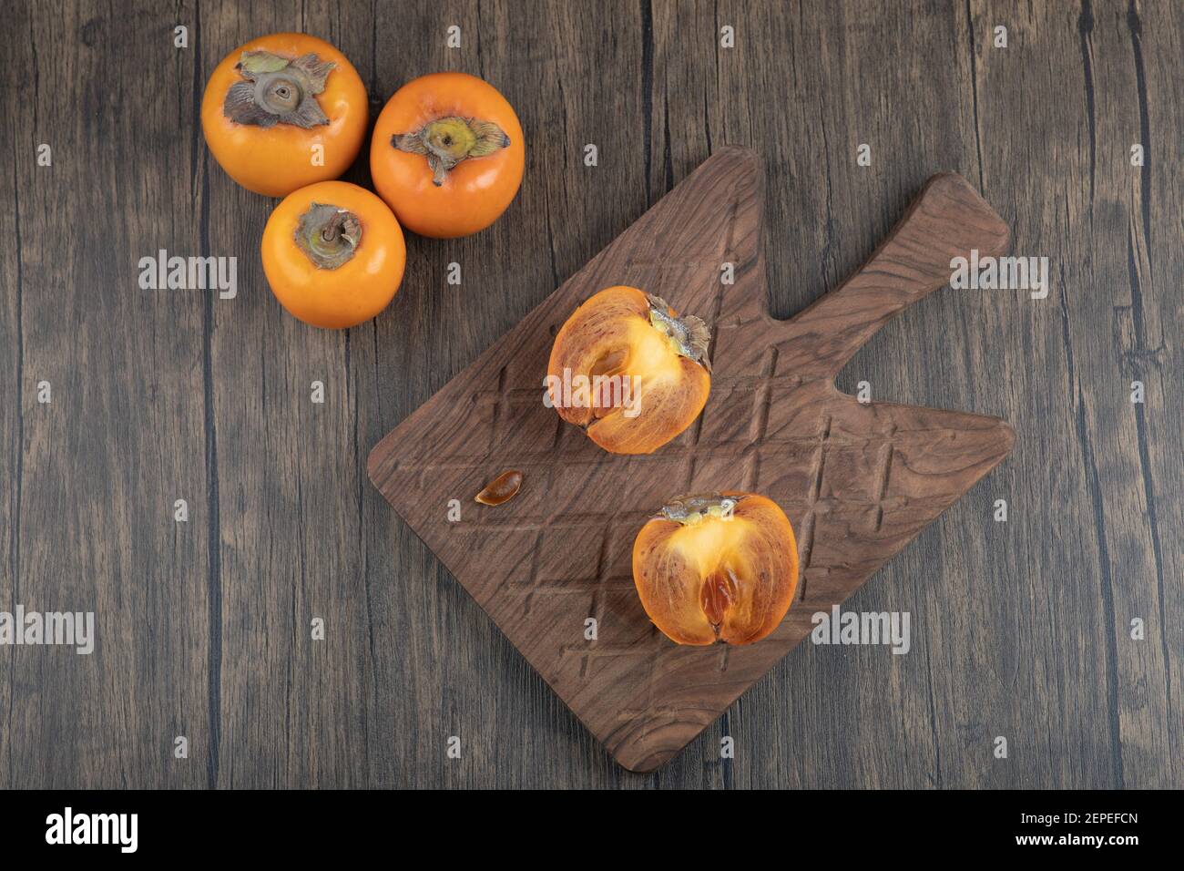 Frutta fuyu persimmon a metà fette su tagliere di legno Foto Stock