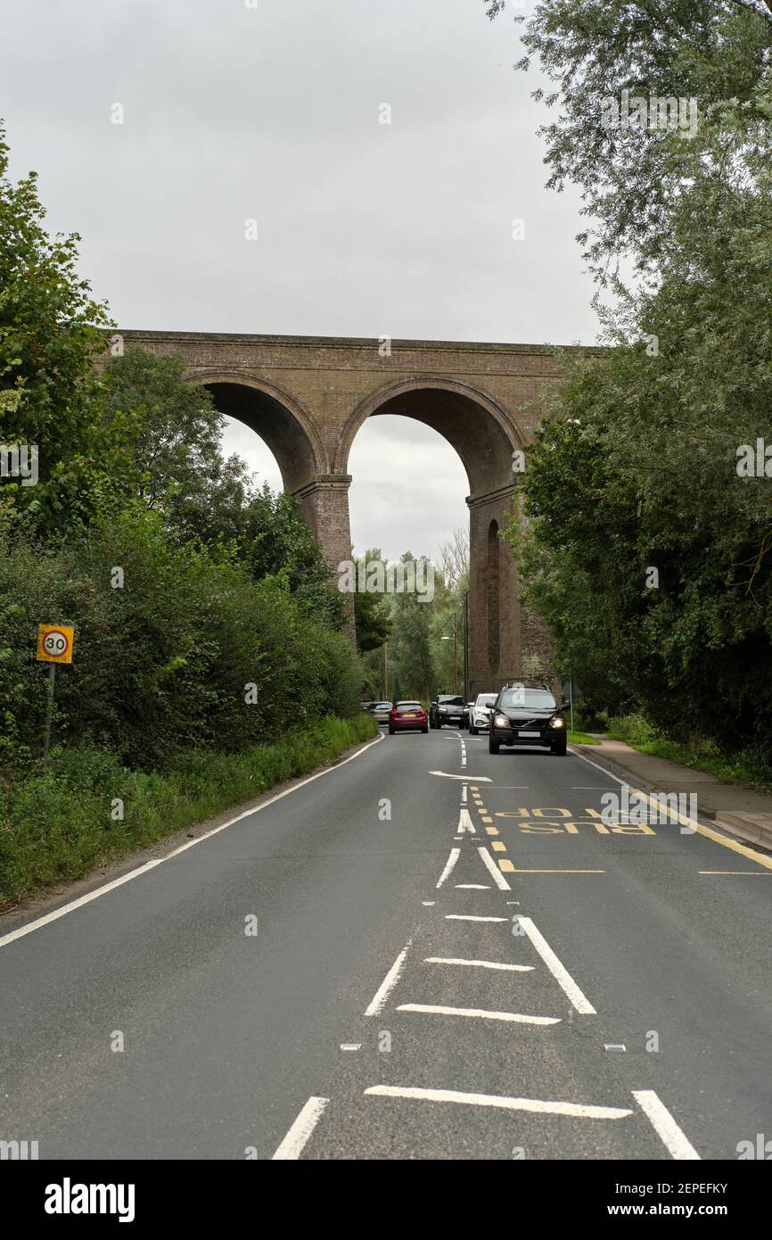 Auto che viaggiano lungo una strada sotto Chappel Viaduct, Chappel, Colchester, Essex, Regno Unito Foto Stock