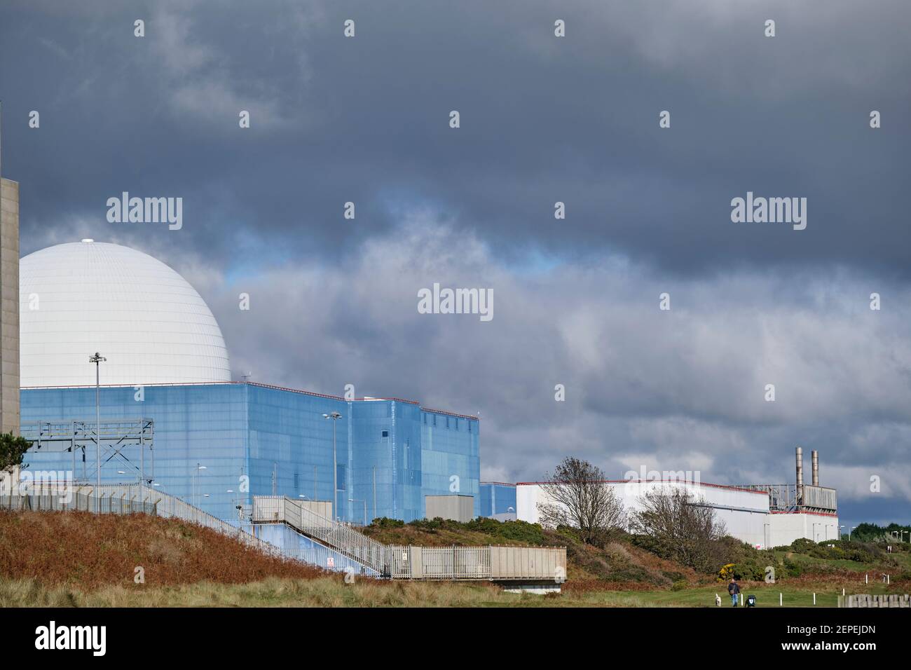 Moody nuvole scure sopra l'edificio del reattore Sizewell B a Sizewell, Suffolk. La cupola bianca, rivestimento blu dell'edificio del reattore Foto Stock