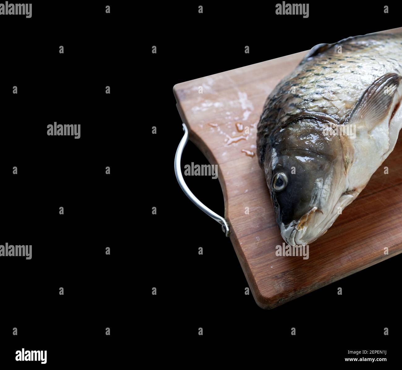 scongelamento del pesce carpa su tagliere di legno isolato su nero sfondo Foto Stock