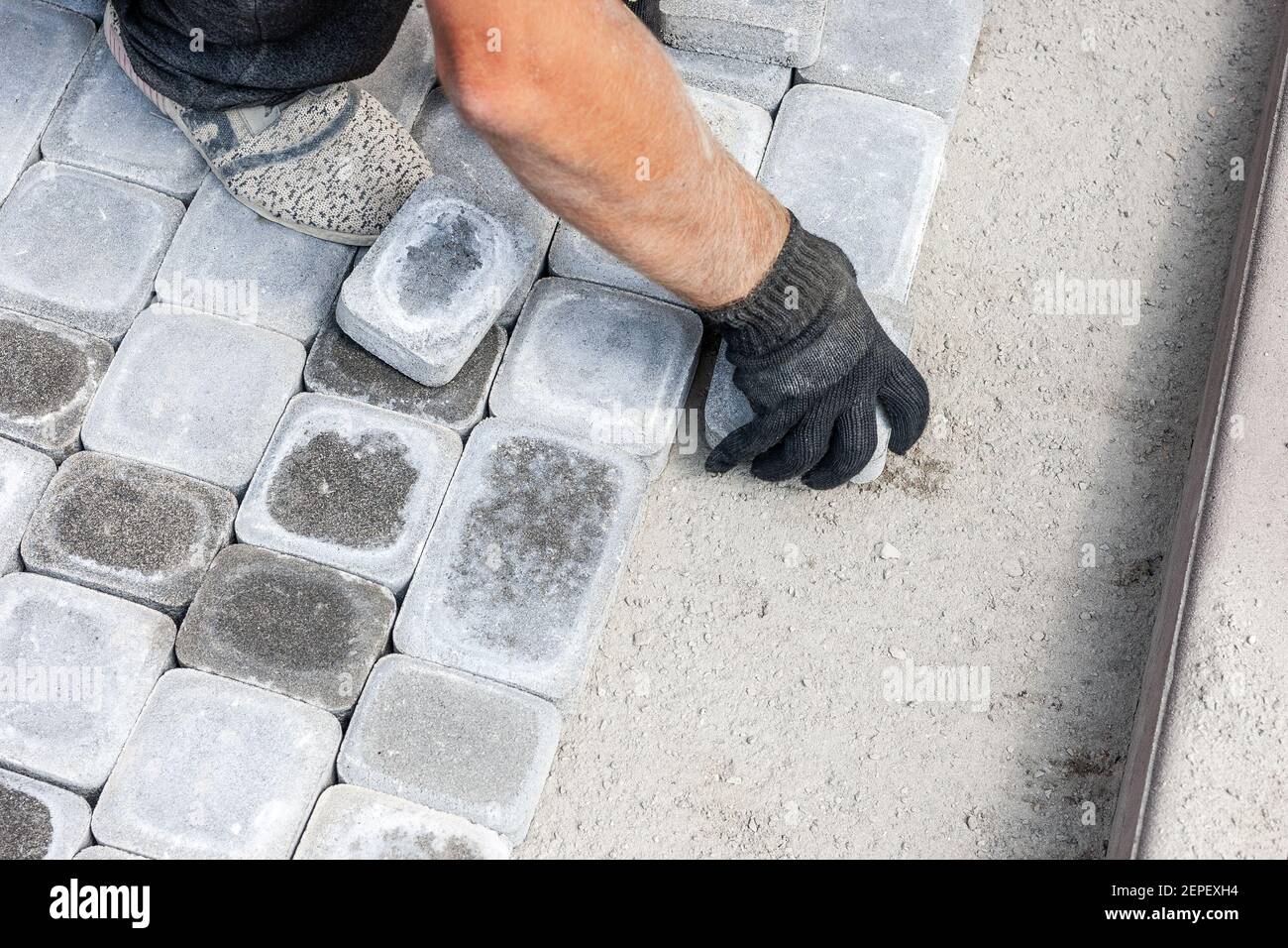 lavoratore installare nuovi mattoni o blocco di lastra a pathway. piastrelle di pavimentazione per le riparazioni stradali Foto Stock