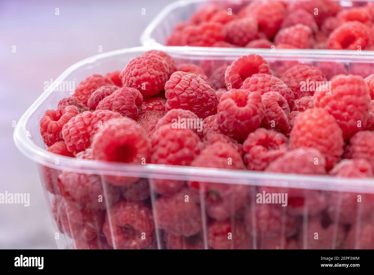 Pila di lamponi crudi in contenitore di plastica. Consistenza, sfondo. Bacche da dessert fresche Foto Stock