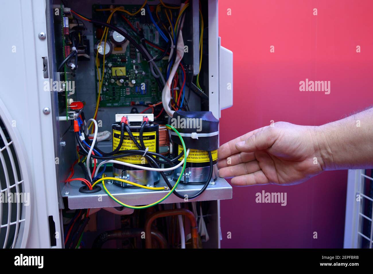 Mano dell'uomo che punta sull'unità di controllo elettronico del moderno condizionatore d'aria smontato. Foto Stock