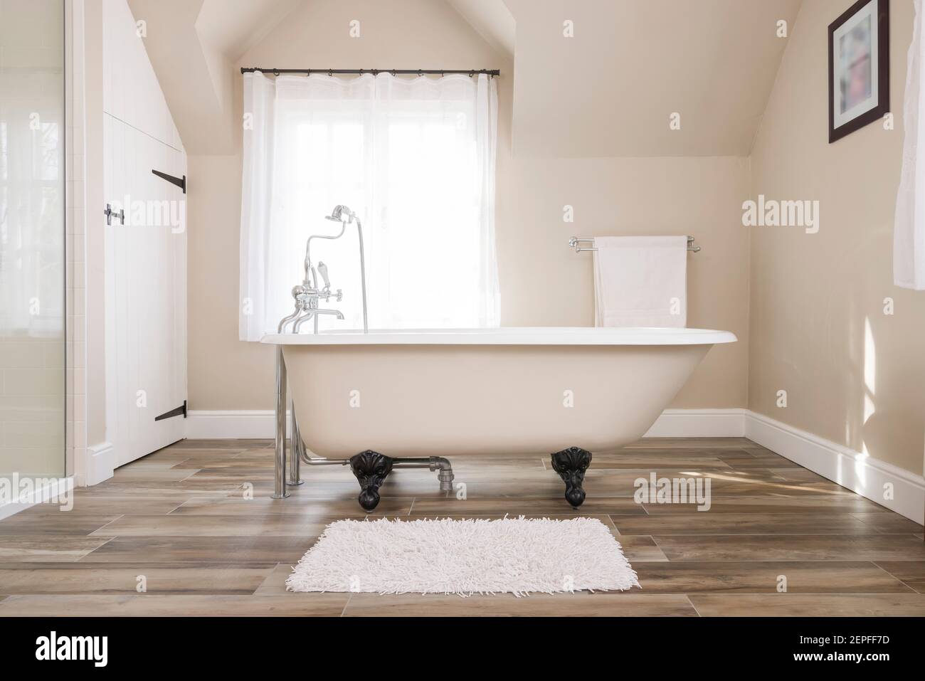 Interni del bagno, lussuoso bagno dal design moderno con vasca per disabili e una finestra sullo sfondo, Regno Unito Foto Stock