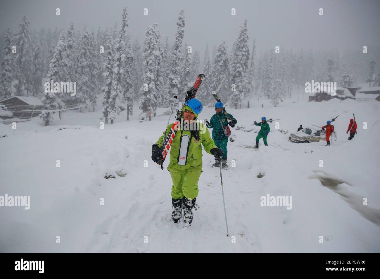 Srinagar, Kashmir. 27 Feb 2021. Gli sciatori camminano tra le nevicate in una stazione sciistica di Gulmarg, a circa 48 km a nord di Srinagar, la capitale estiva del Kashmir, 27 febbraio 2021. Credit: Javed Dar/Xinhua/Alamy Live News Foto Stock