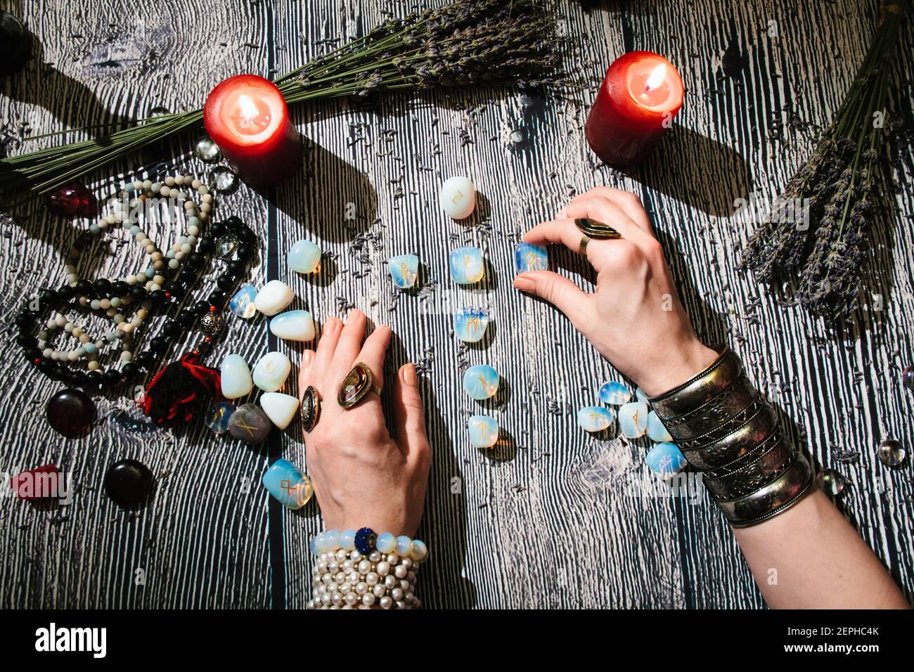 Mani di fortuneteller con rune di pietra, vista dall'alto. Previsione del futuro. Foto Stock