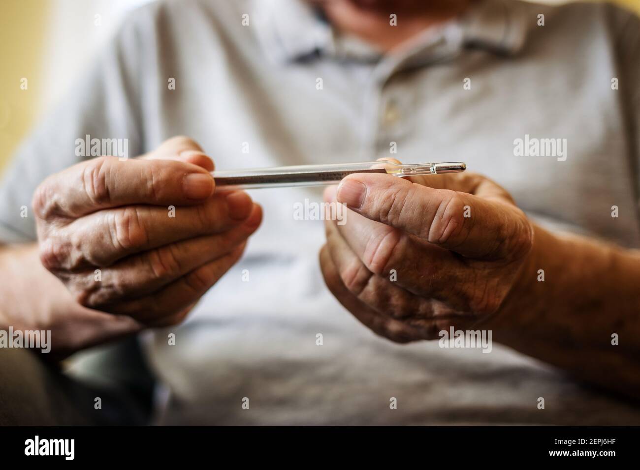 L'uomo anziano sta misurando la sua temperatura corporea con un termometro. Coronavirus, virus influenzale e febbre. Concetto di assistenza sanitaria con le persone Foto Stock