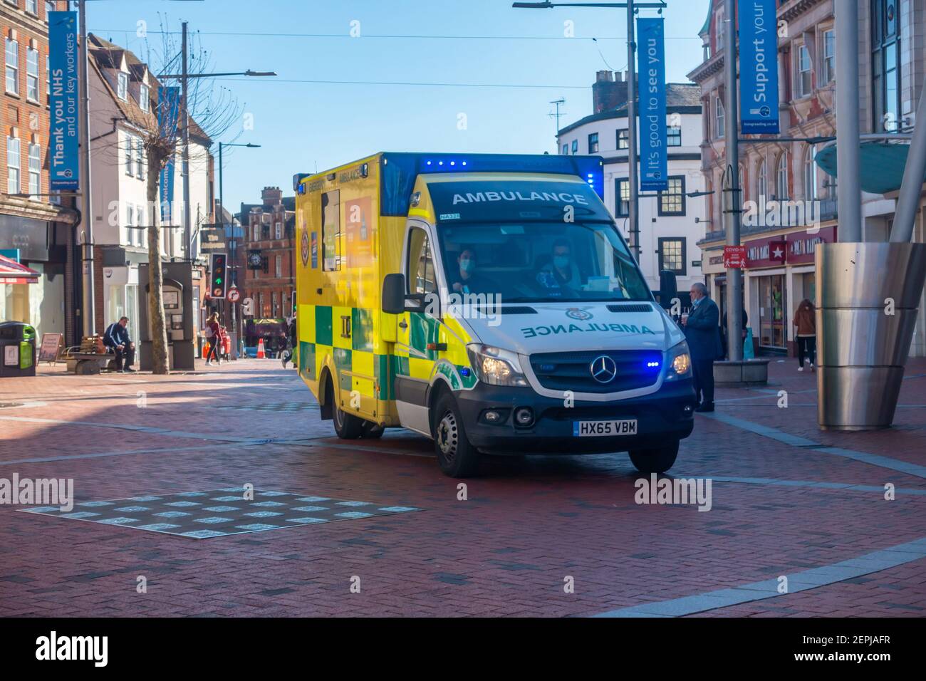 Un'ambulanza con luci blu lampeggianti lo fa strada con attenzione lungo Broadstreet a Reading, UK, una strada pedonale nel centro della città. Foto Stock