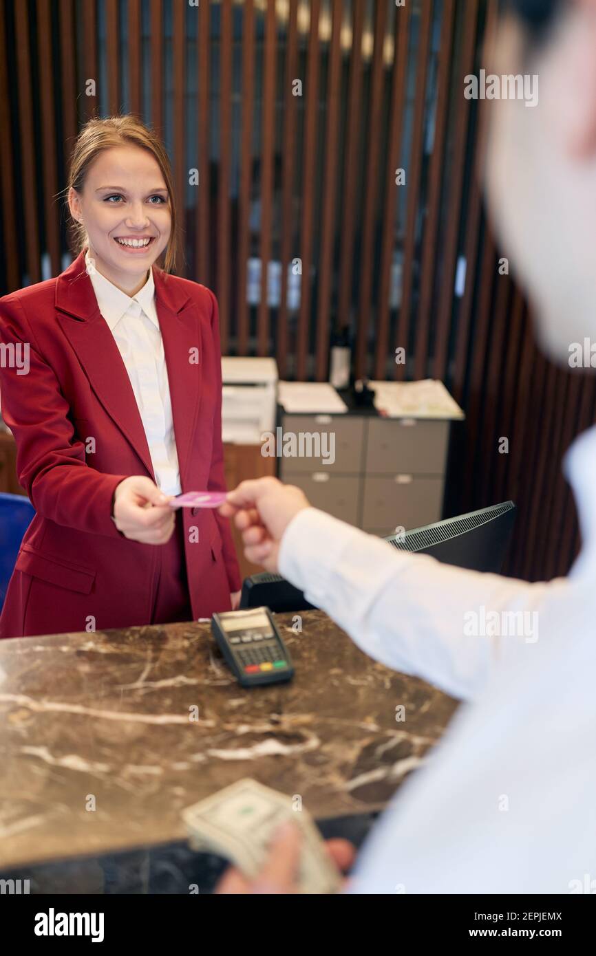 Una piacevole addetta alla reception dietro il banco che riceve gli ospiti presso l'hotel. Turismo, affari, hotel Foto Stock