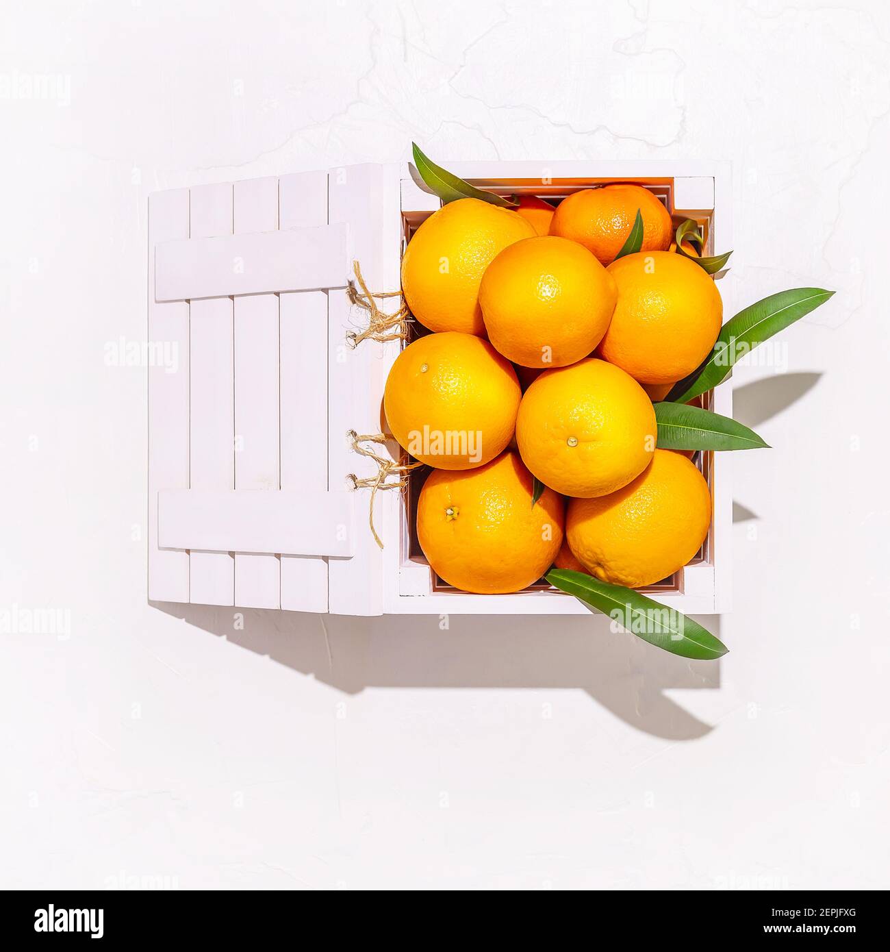 Arancio fresco con foglie in una scatola di legno su sfondo bianco. Alimenti sani di stagione con un sacco di vitamine. Cibi ricchi di vitamina C. Eco friendly Frui Foto Stock