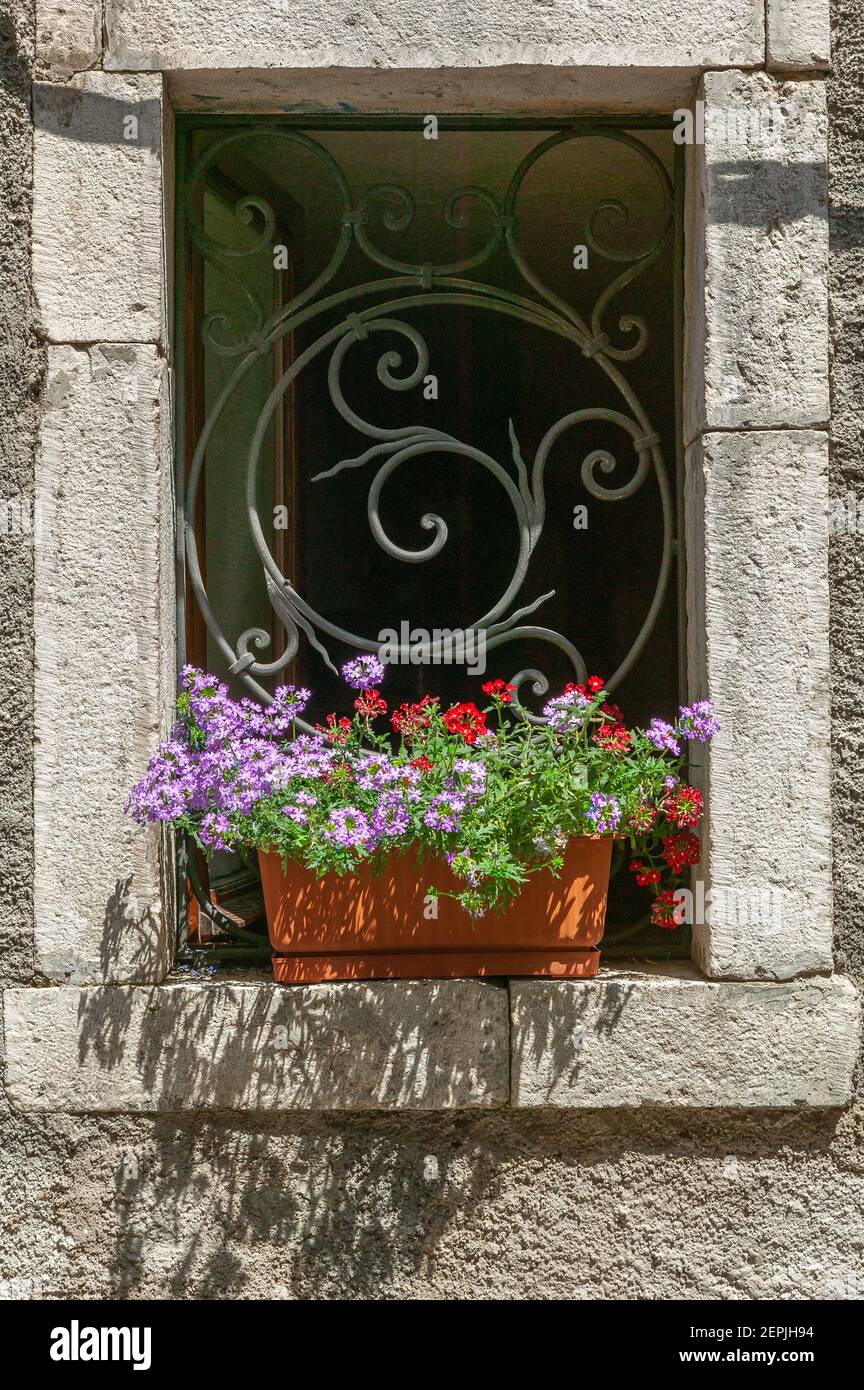 finestra in pietra con piantatrice e decorazione in ferro Foto Stock