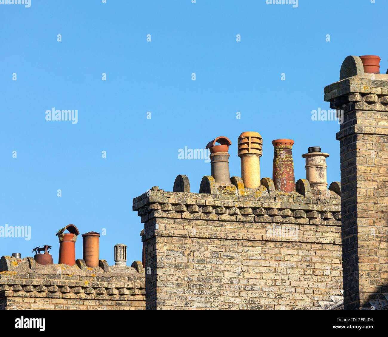 Grande camino vittoriano in mattoni con camino misto pentole visto contro un cielo blu Foto Stock