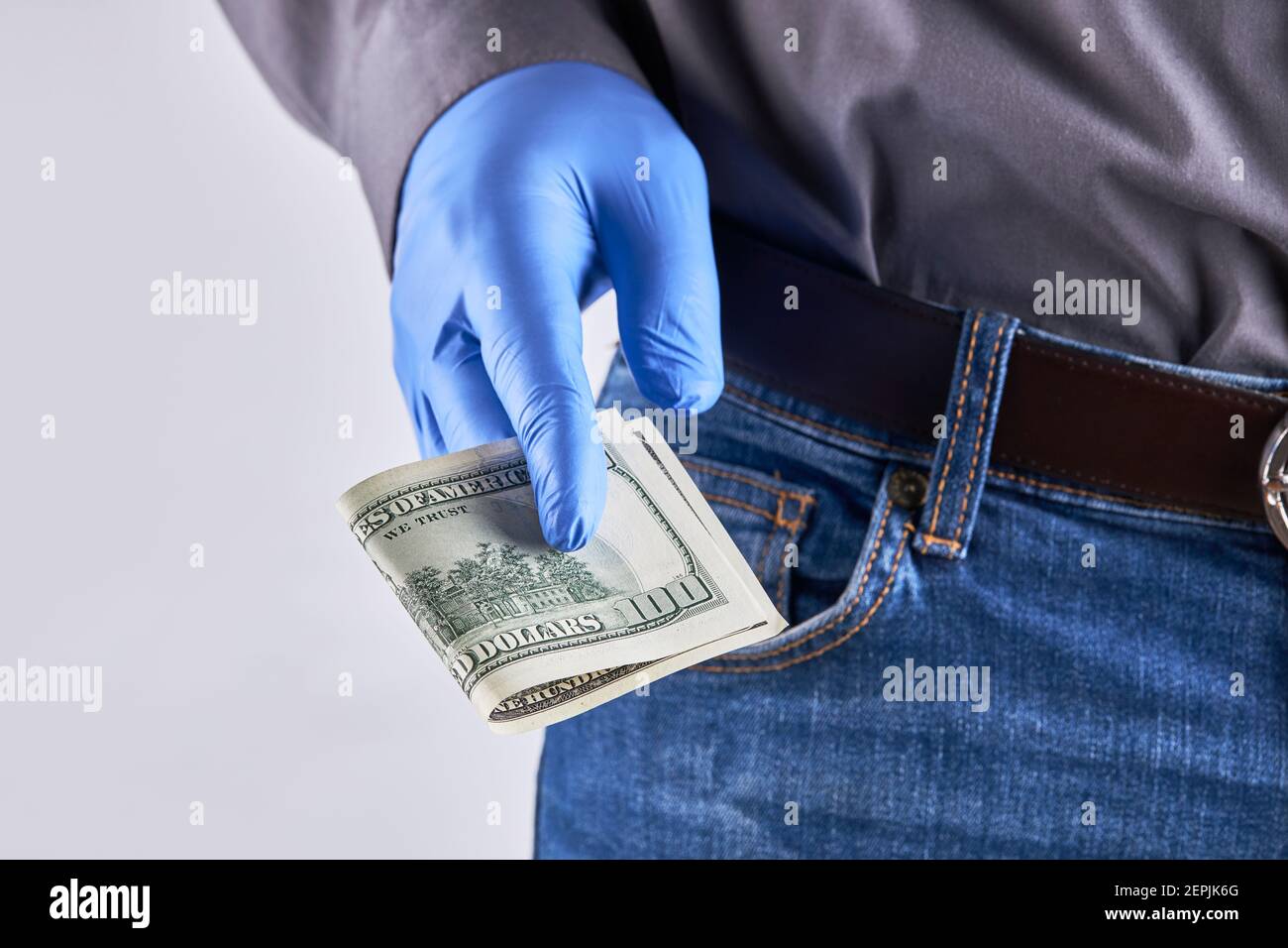 uomo che indossa camicia, jeans blu e guanti protettivi in lattice. Dare denaro gesto. Protezione in tempo pandemico Foto Stock