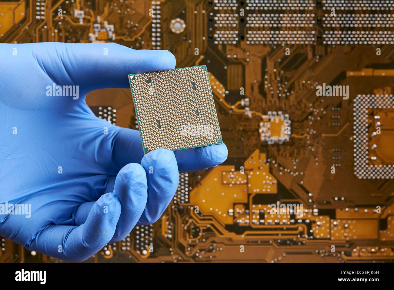 il tecnico tiene l'unità processore centrale della cpu sullo sfondo della scheda a circuito stampato. concetto di ricerca hardware Foto Stock
