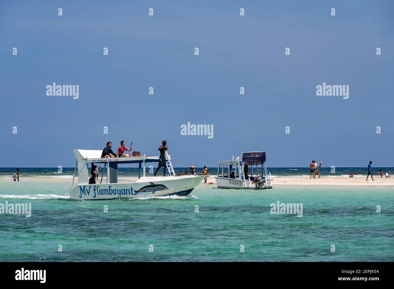 Una barca con fondo di vetro ormeggiata da una bassa riva di sabbia con persone sulla sabbia, Diani, Kenya Foto Stock