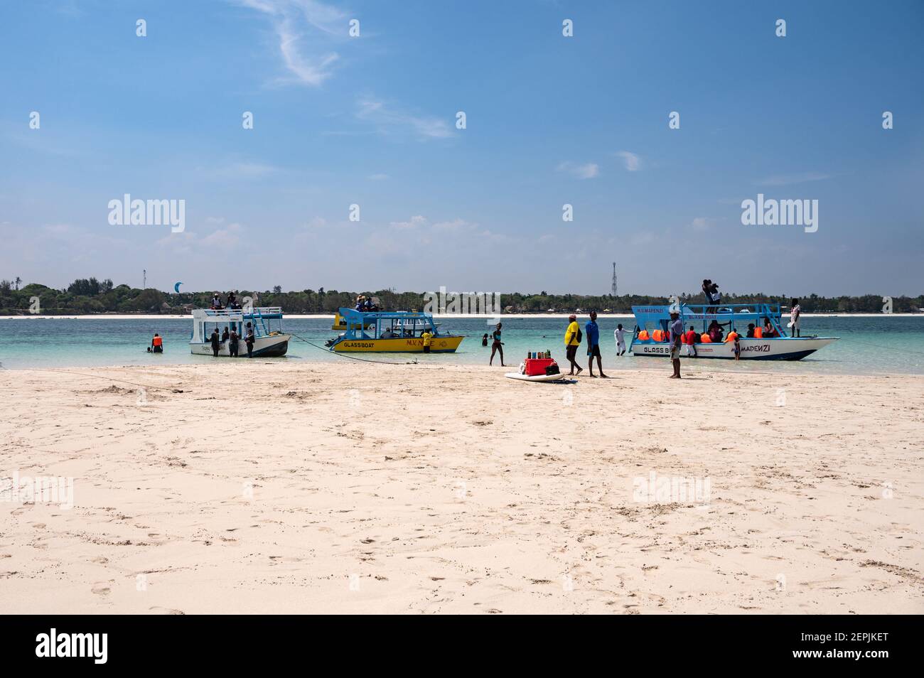 Una barca con fondo di vetro ormeggiata da una bassa riva di sabbia con persone sulla sabbia, Diani, Kenya Foto Stock