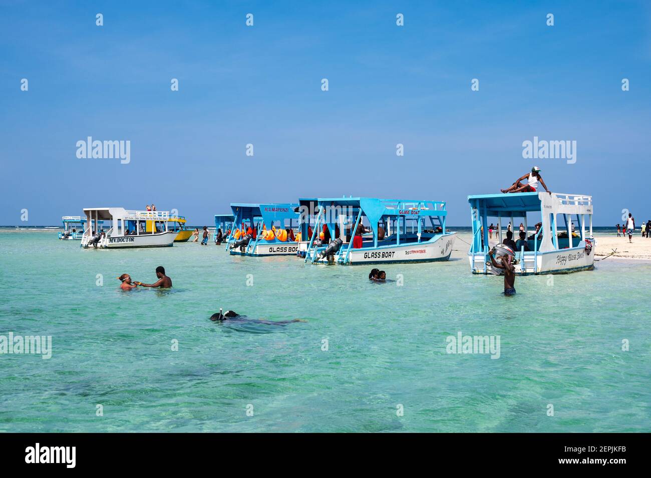 Una barca con fondo di vetro ormeggiata da una bassa riva di sabbia con persone sulla sabbia, Diani, Kenya Foto Stock