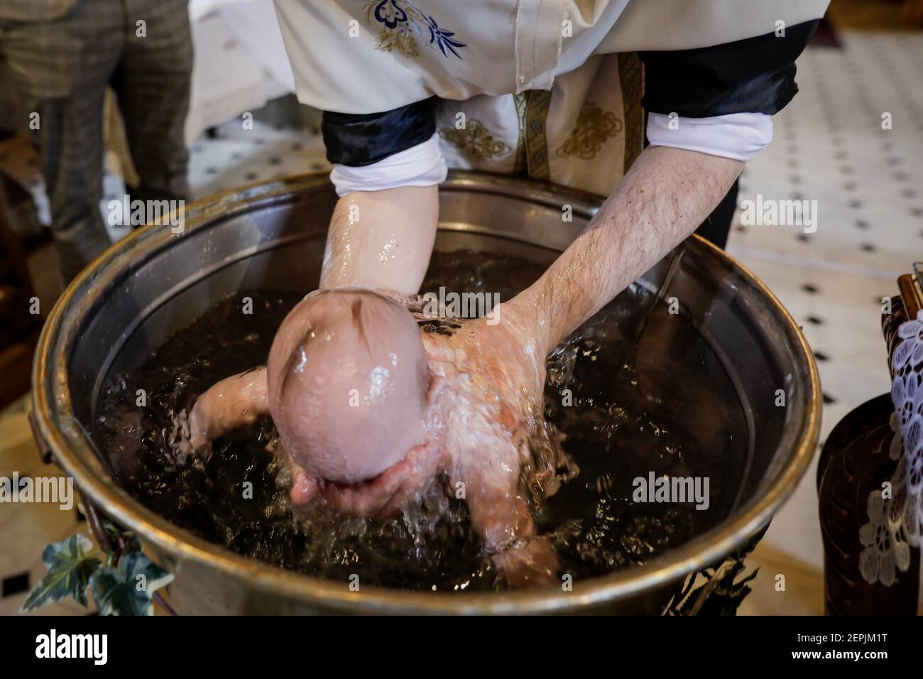 Bucarest, Romania - 24 maggio 2020: Dettagli su un bambino affondato nel fonte battesimale da un sacerdote ortodosso durante la cerimonia del battesimo. Foto Stock