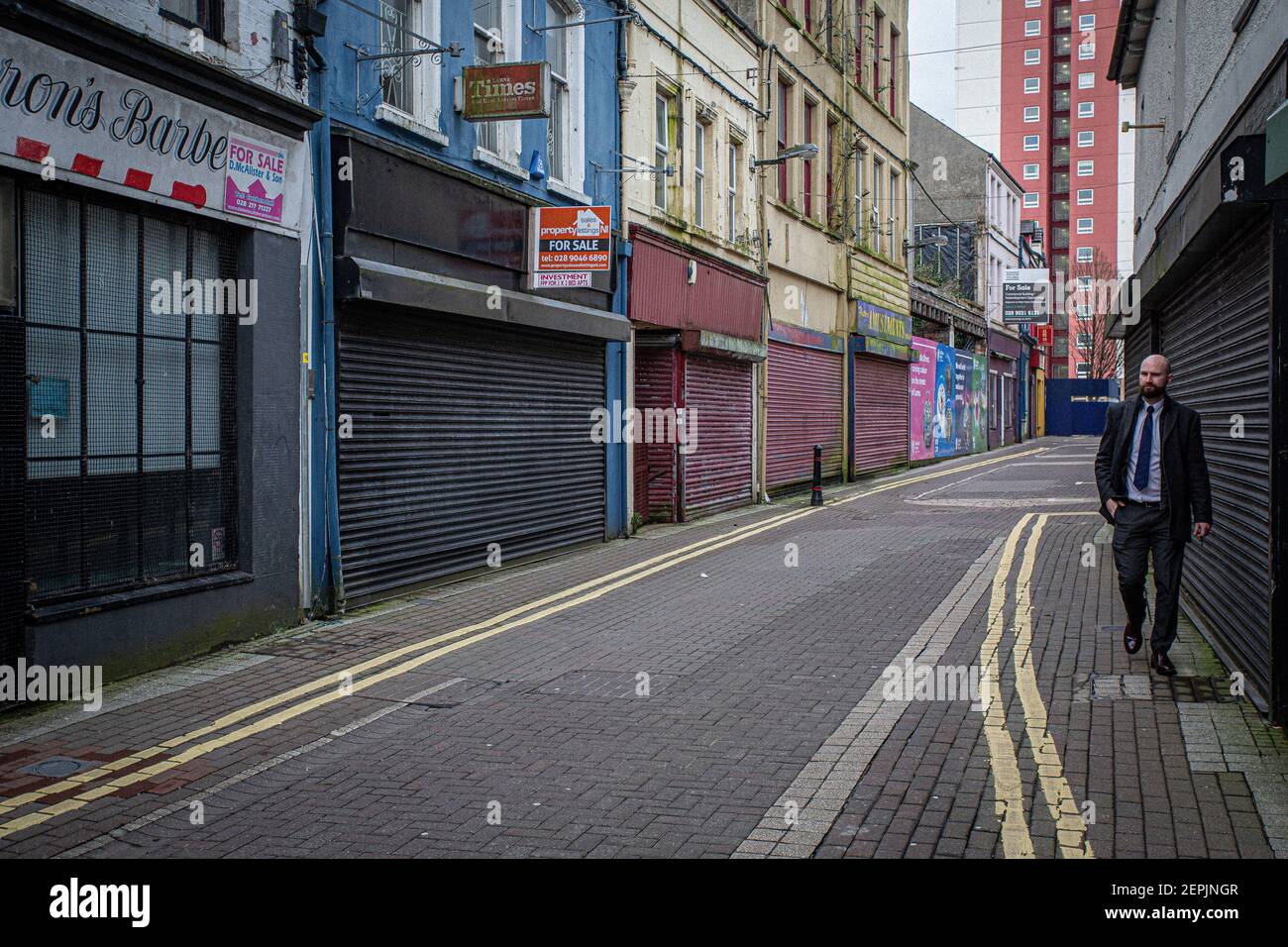 LARNE, IRLANDA DEL NORD - Febbraio, 24 : UN uomo cammina attraverso i negozi chiusi a causa della pandemia COVID-19 a Larne . Foto Stock