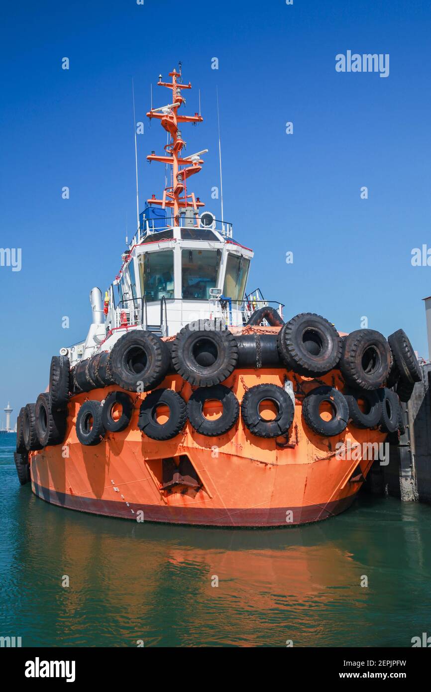 In un porto dell'Arabia Saudita è ormeggiata una barca da rimorchiatore con scafo arancione brillante. Foto verticale Foto Stock