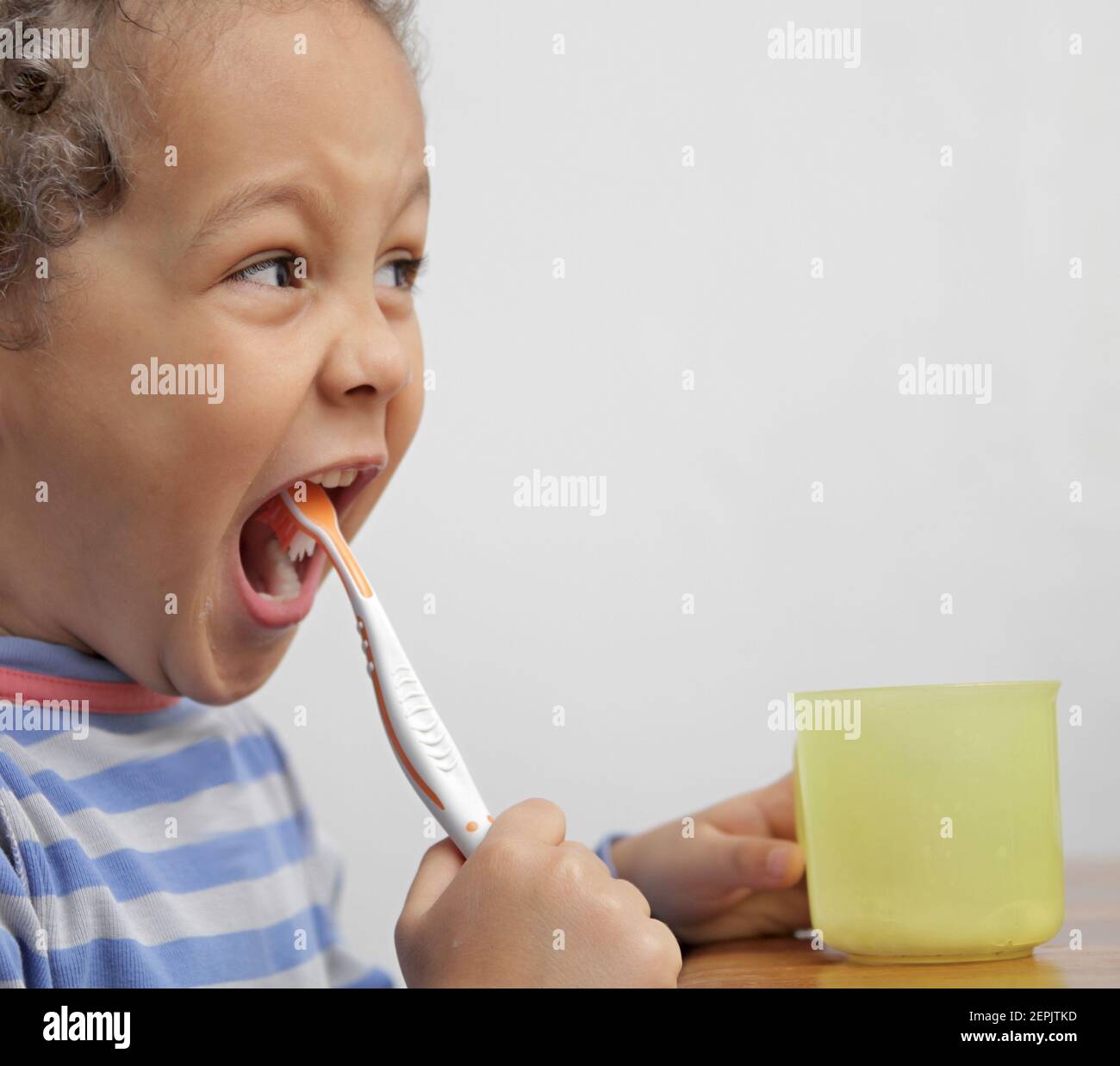 ragazzo spazzolando i denti con una spazzola elettrica con sfondo grigio foto stock Foto Stock