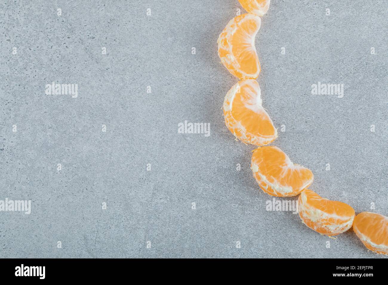 Fette di delizioso mandarino su sfondo grigio Foto Stock
