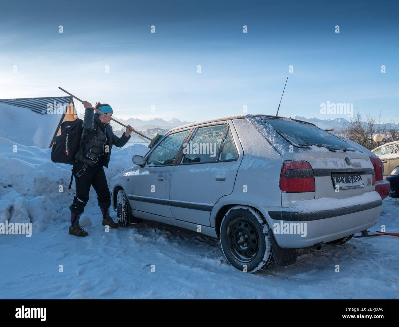 Una giovane donna che pulisce un'auto dalla neve, Bukowina T, Polonia Foto Stock