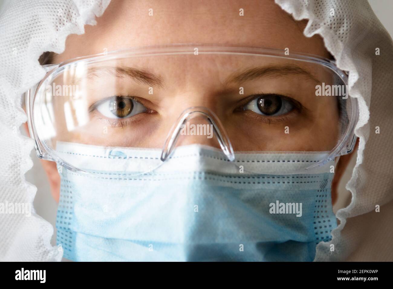 Medico o infermiere in tuta professionale a causa della pandemia del coronavirus COVID-19, ritratto del medico in primo piano con i dispositivi di protezione individuale (PPE), occhi Foto Stock