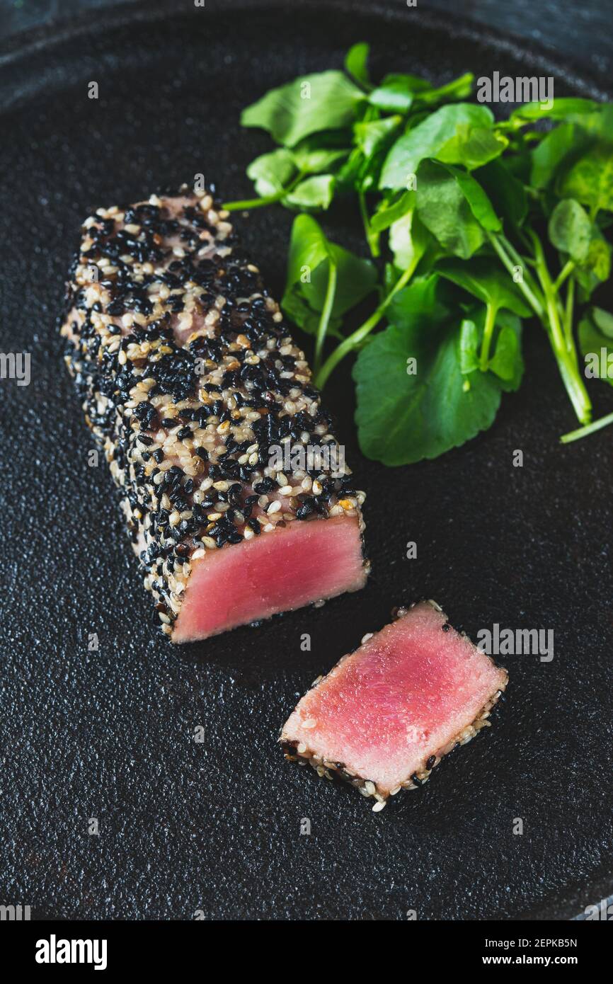 Bistecca di tonno fritta in sesamo nero con asparagi nero piastra Foto Stock