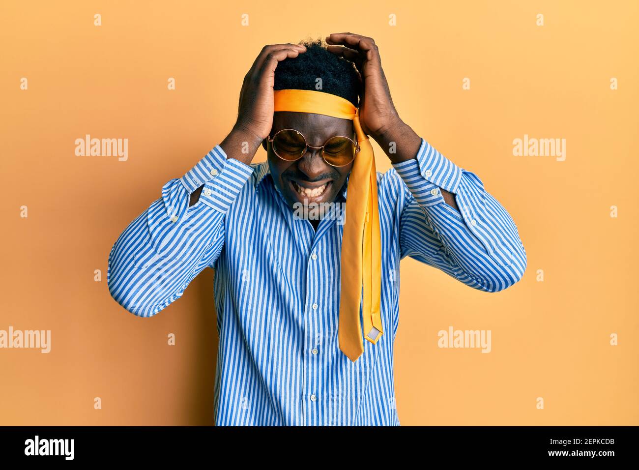 Bell'uomo nero ubriaco che indossa cravatta sulla testa e occhiali da sole  che soffrono di mal di testa disperata e stressata perché dolore ed  emicrania. Mani sulla testa Foto stock - Alamy