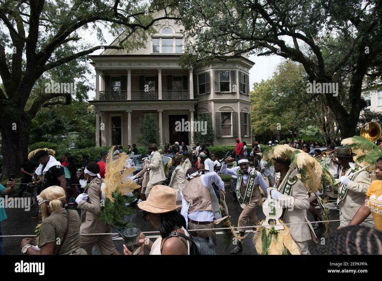 Una vibrante parata di seconda linea si svolge davanti alle signorili residenze di Uptown a New Orleans, mostrando la ricchezza culturale e lo spirito comunitario della città. Foto Stock