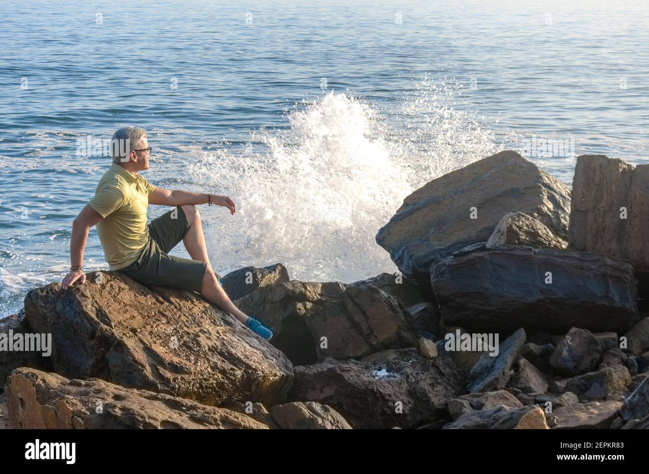 Uomo che medita sulla roccia nella costa della spiaggia Foto Stock